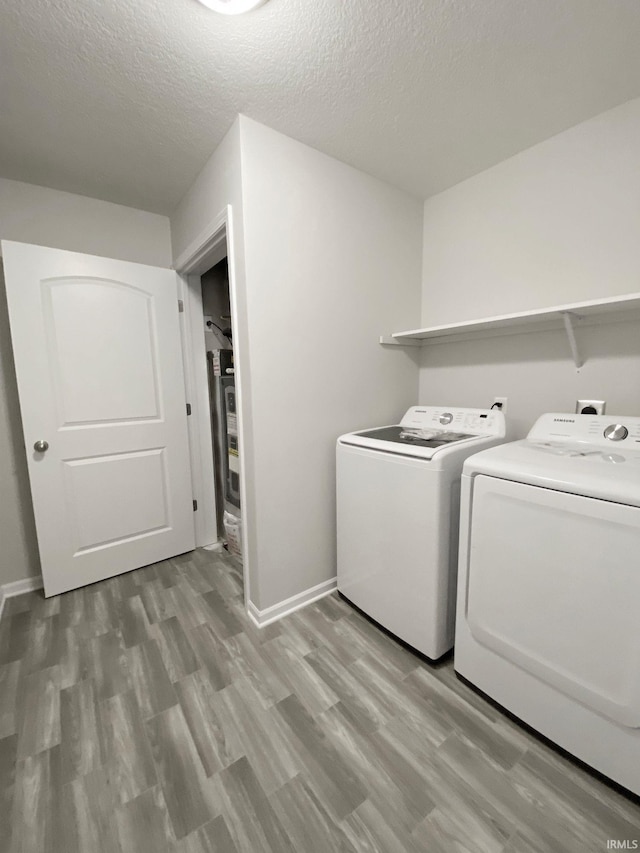 laundry area with a textured ceiling, light hardwood / wood-style flooring, and washing machine and clothes dryer