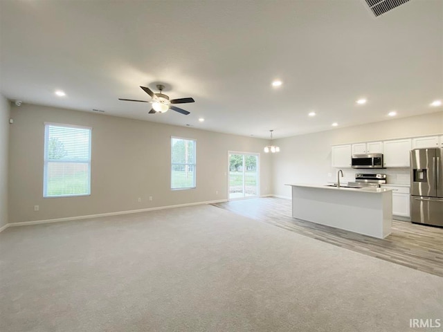 kitchen with white cabinets, sink, an island with sink, appliances with stainless steel finishes, and decorative light fixtures