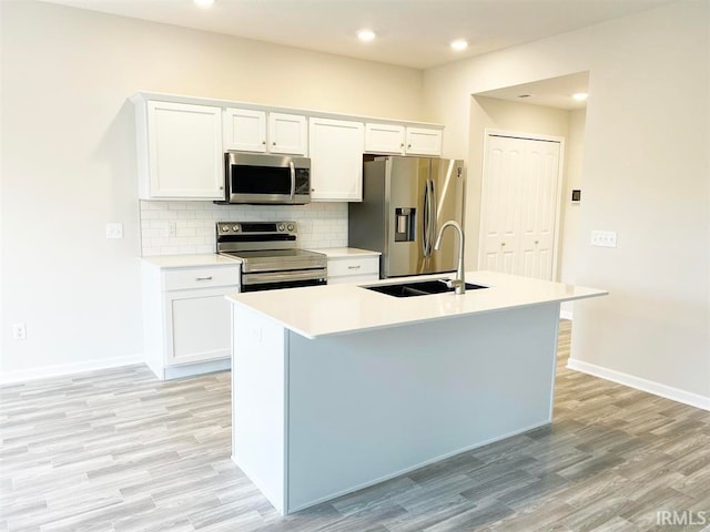 kitchen featuring stainless steel appliances, white cabinetry, a center island with sink, and sink