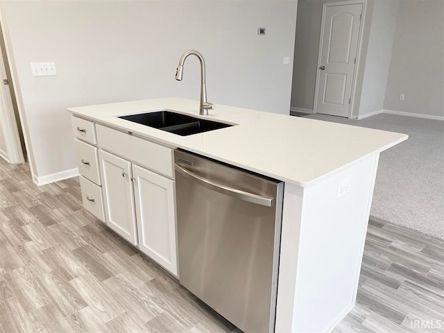 kitchen with white cabinets, sink, dishwasher, light hardwood / wood-style floors, and an island with sink