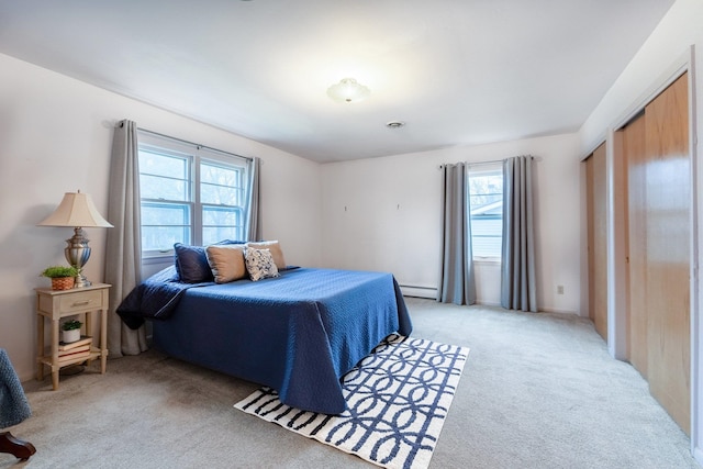 carpeted bedroom with a closet, multiple windows, and a baseboard heating unit