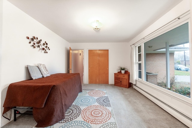 bedroom featuring light carpet and a baseboard heating unit