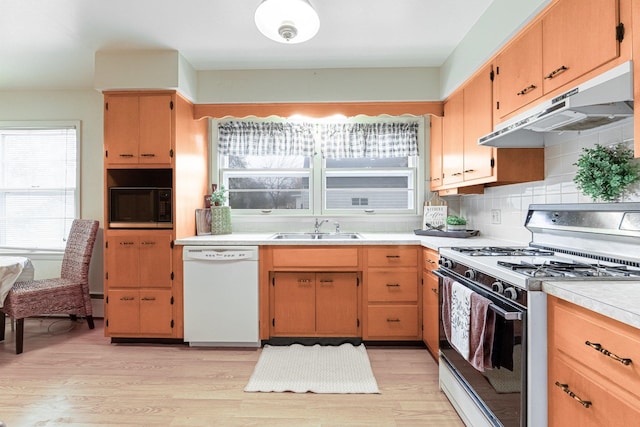 kitchen featuring light wood-type flooring, white appliances, backsplash, and sink