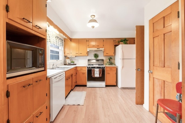 kitchen with decorative backsplash, light wood-type flooring, white appliances, and sink