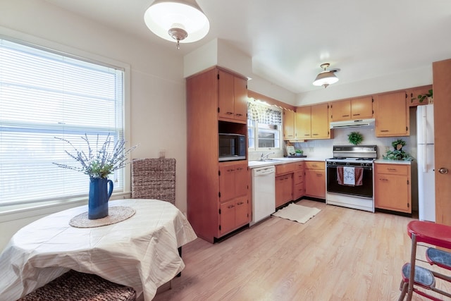 kitchen with white appliances, light hardwood / wood-style floors, tasteful backsplash, and sink