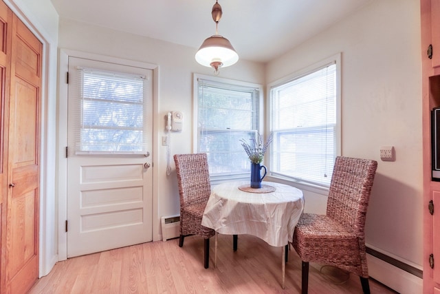 dining space featuring a healthy amount of sunlight, a baseboard radiator, and light hardwood / wood-style floors