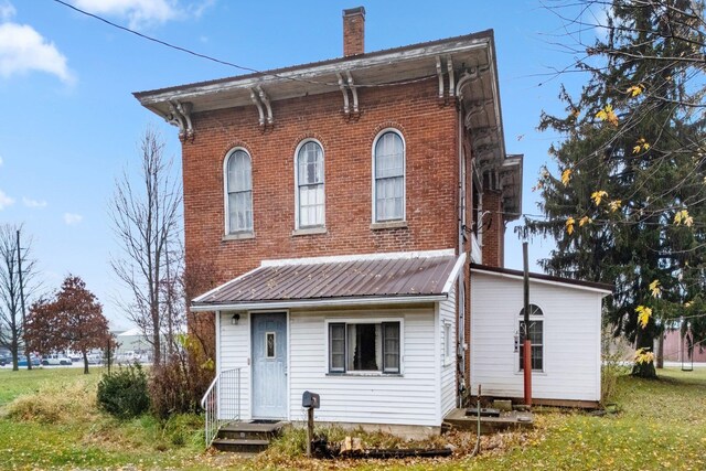 205 W Swager Dr, Fremont, IN 46737 - back of house featuring a chimney, a metal roof, brick siding, and a lawn