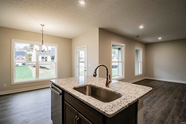 kitchen featuring dark hardwood / wood-style flooring, a center island with sink, decorative light fixtures, and sink