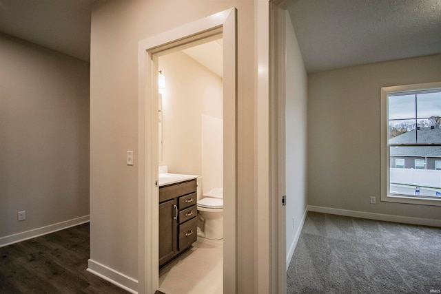 bathroom featuring vanity, toilet, lofted ceiling, and a textured ceiling