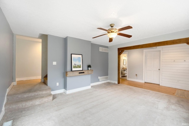 unfurnished living room featuring light carpet, ceiling fan, and a textured ceiling