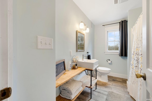 bathroom with wood-type flooring, toilet, and sink