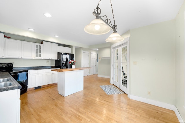 kitchen with a kitchen island, black appliances, decorative light fixtures, and light wood-type flooring