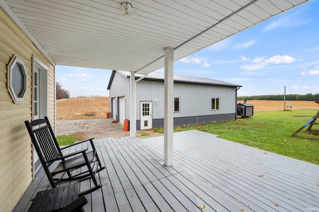 wooden terrace featuring a lawn, a rural view, and a garage