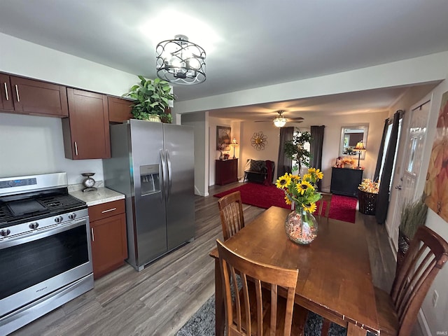 kitchen featuring hardwood / wood-style flooring, ceiling fan with notable chandelier, dark brown cabinetry, and stainless steel appliances