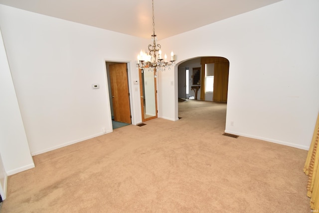 unfurnished room featuring light colored carpet and a notable chandelier