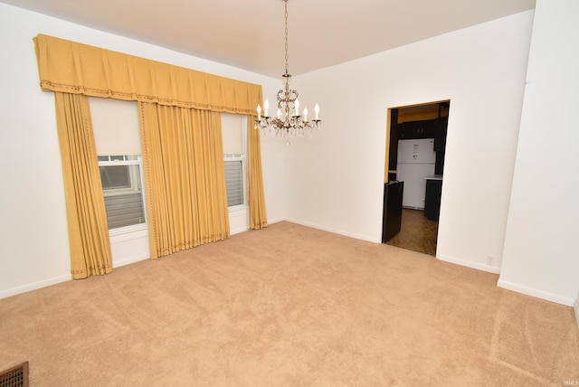 carpeted spare room featuring a notable chandelier