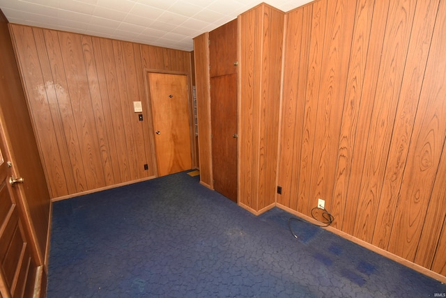 carpeted spare room featuring wood walls