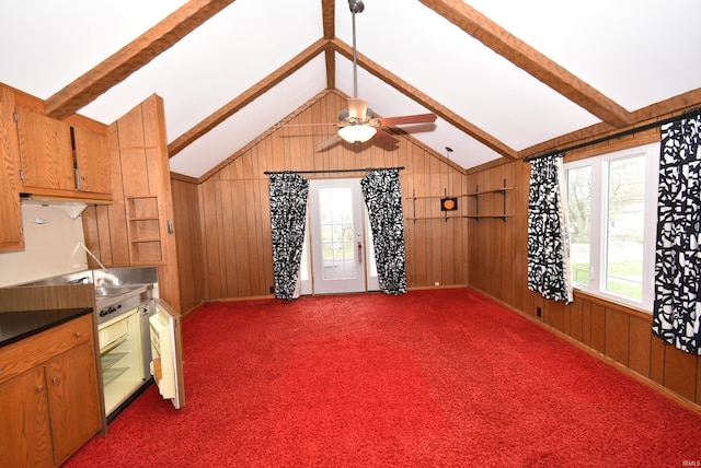 interior space featuring wood walls, vaulted ceiling with beams, dark carpet, and ceiling fan