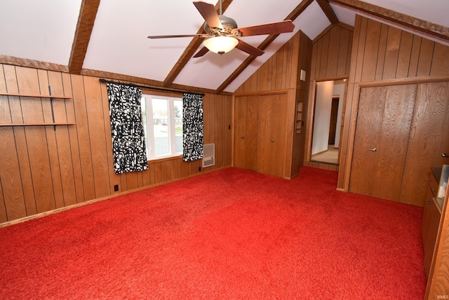 interior space featuring vaulted ceiling with beams, wood walls, ceiling fan, and light colored carpet