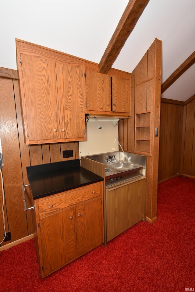 kitchen with wooden walls, beamed ceiling, and dark colored carpet