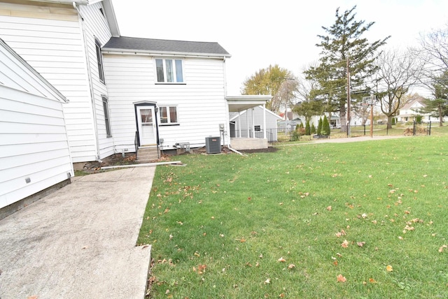 rear view of property with central AC unit and a lawn