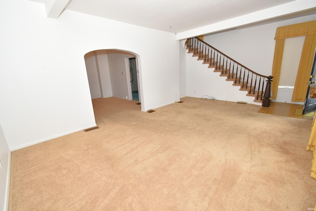 unfurnished room with beamed ceiling and light carpet