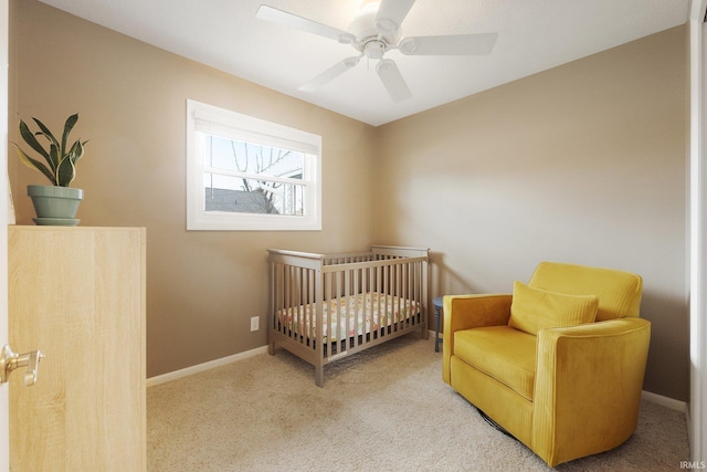 carpeted bedroom with ceiling fan and a nursery area