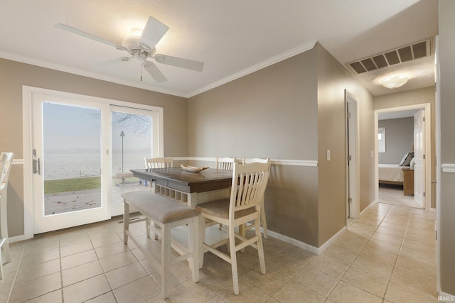 dining area featuring ceiling fan, a water view, light tile patterned floors, and crown molding