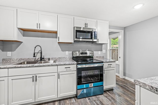 kitchen with light stone counters, stainless steel appliances, dark wood-type flooring, sink, and white cabinets