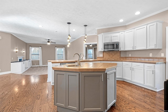 kitchen with white cabinets, wood-type flooring, a kitchen island with sink, and sink