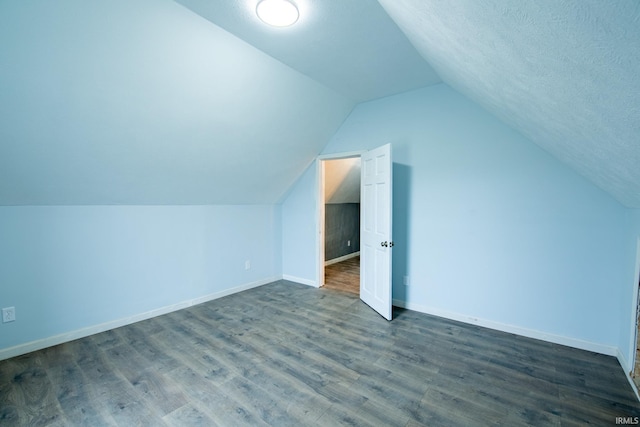 additional living space with dark hardwood / wood-style flooring, a textured ceiling, and vaulted ceiling