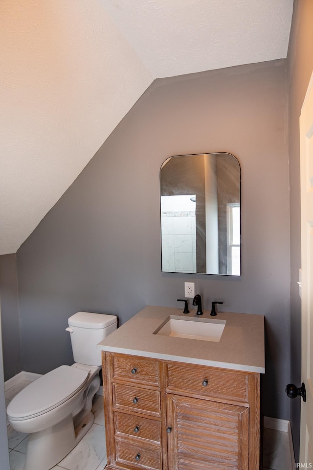 bathroom with toilet, vanity, and vaulted ceiling