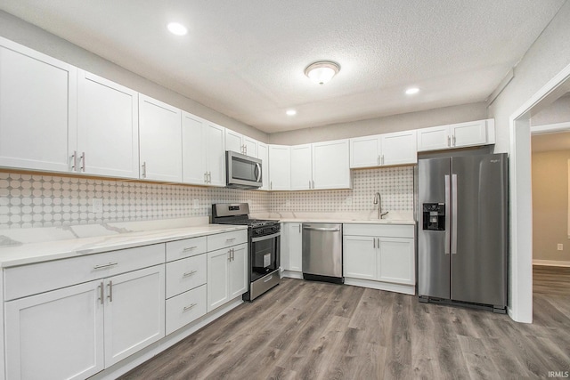 kitchen featuring backsplash, white cabinets, light hardwood / wood-style floors, and appliances with stainless steel finishes