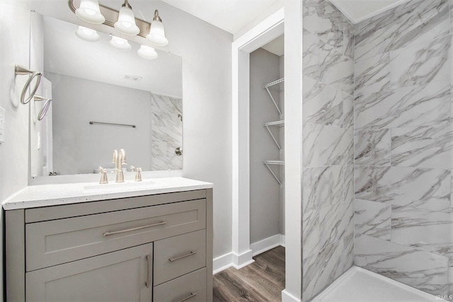 bathroom featuring hardwood / wood-style flooring, vanity, and tiled shower