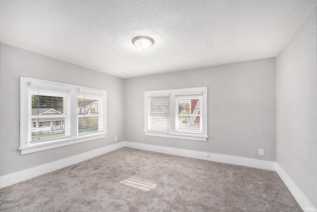 unfurnished room featuring carpet flooring, a healthy amount of sunlight, and a textured ceiling