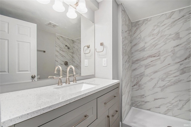 bathroom with a tile shower and vanity