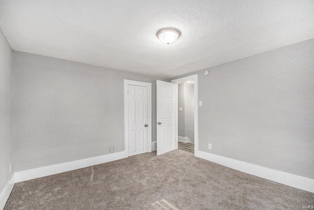 carpeted empty room featuring a textured ceiling