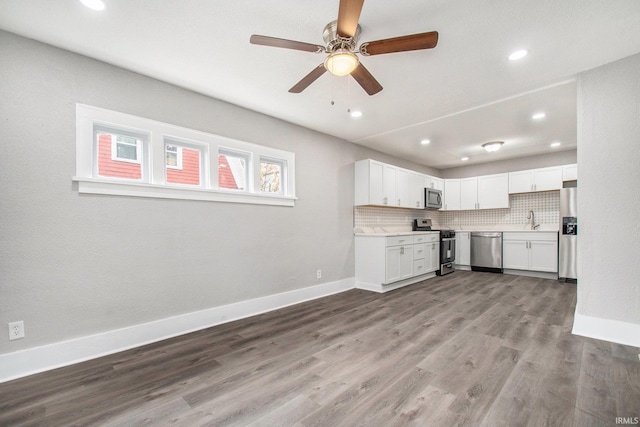 kitchen featuring tasteful backsplash, stainless steel appliances, sink, hardwood / wood-style floors, and white cabinetry