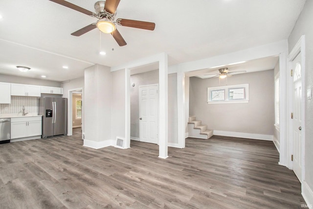 unfurnished living room featuring sink, plenty of natural light, and light wood-type flooring