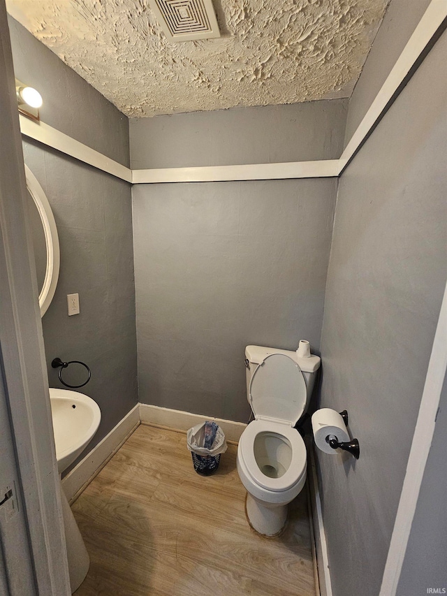 bathroom featuring wood-type flooring, a textured ceiling, and toilet