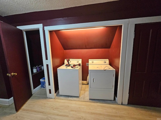 laundry area with washing machine and clothes dryer, a textured ceiling, and light hardwood / wood-style flooring