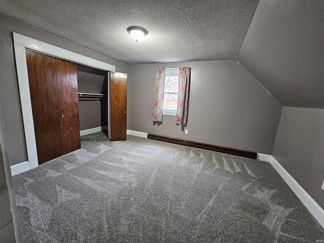 unfurnished bedroom featuring carpet flooring, a textured ceiling, a closet, and lofted ceiling