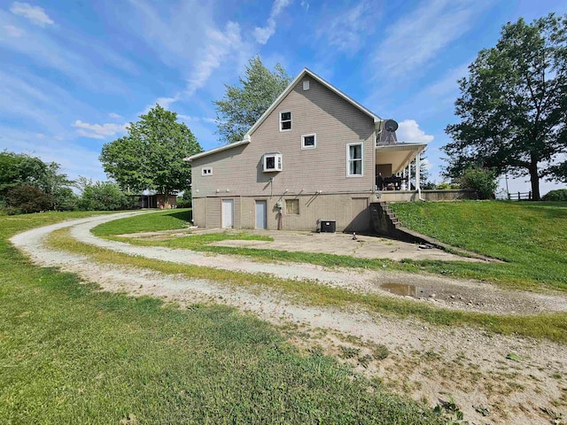 rear view of property with central air condition unit and a yard