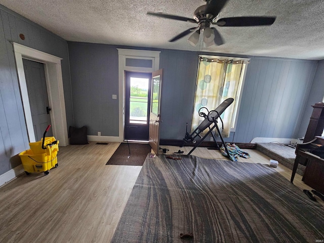 exercise area with ceiling fan, hardwood / wood-style floors, and a textured ceiling