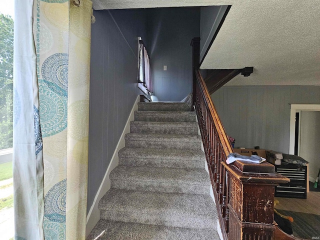 staircase featuring a textured ceiling and carpet floors