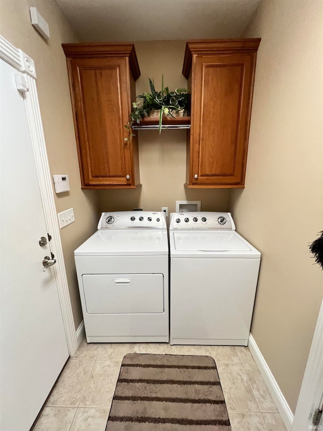 laundry room featuring washer and dryer, light tile patterned floors, and cabinets