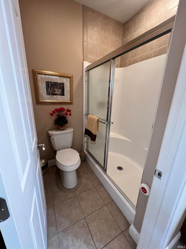 bathroom with tile patterned floors, toilet, and walk in shower