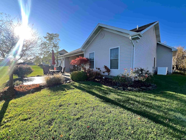 view of side of home featuring a lawn and a patio area