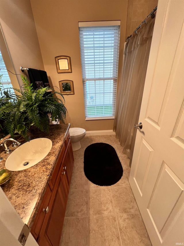 bathroom featuring toilet, vanity, tile patterned floors, and curtained shower