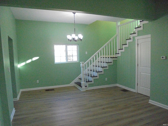 staircase with wood-type flooring and a notable chandelier